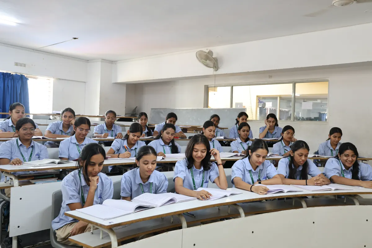 A lecture room with curved desks and students taking notes while a class is in session.
