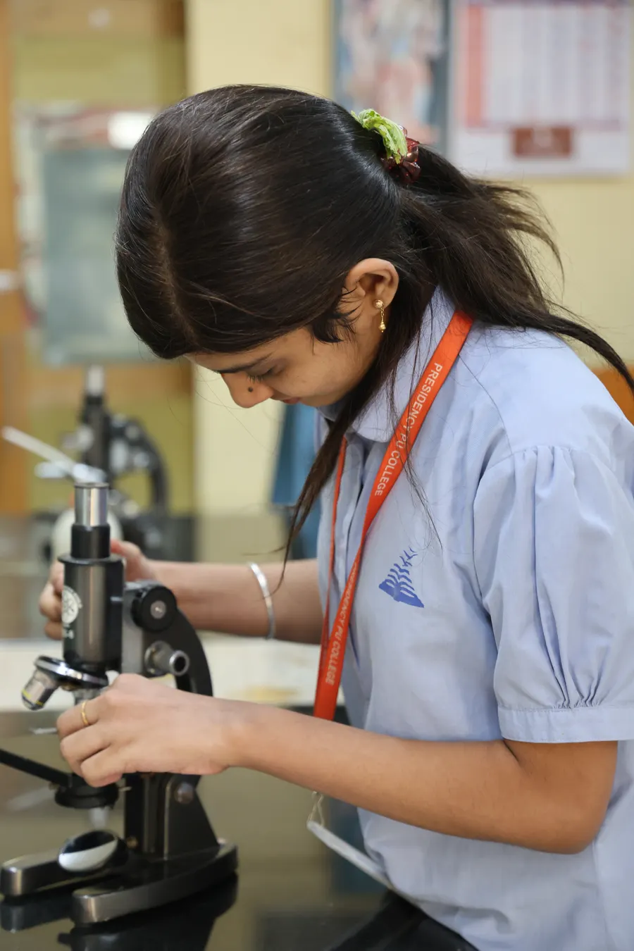 A student leaning over a microscope in the biology lab.