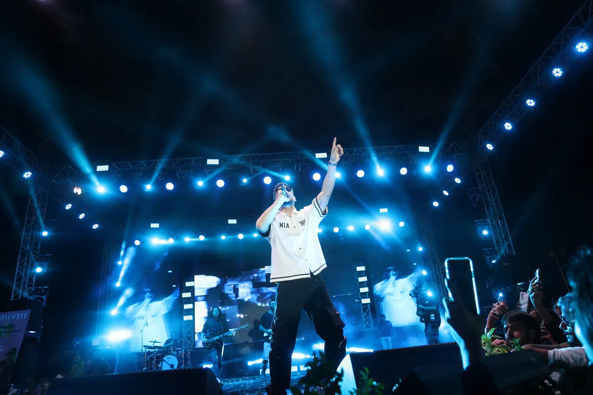 A performer on a lit stage during a campus concert, with confetti in the air.