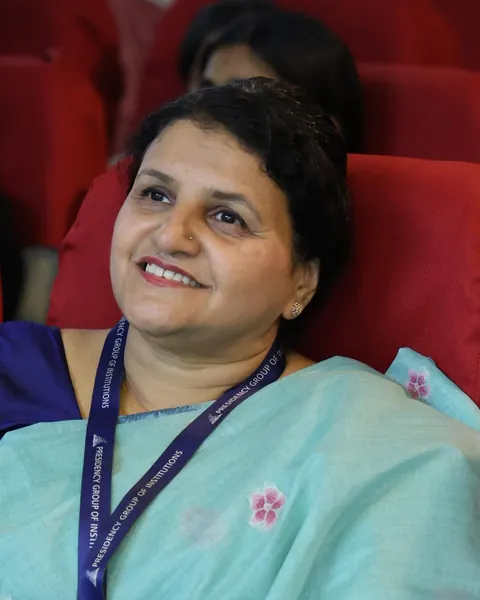 A Presidency PU teacher in a teal saree, smiling during an orientation session.